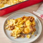 Freshly baked breakfast sausage casserole in a rectangular dish, featuring golden-brown top with visible pieces of sausage and melted cheese.