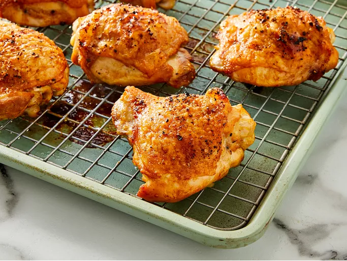 Golden crispy baked chicken thighs on a serving platter, seasoned with garlic, salt, and pepper