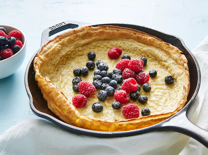 Golden Dutch Baby pancake fresh out of the oven, dusted with confectioners' sugar, served in a cast iron skillet